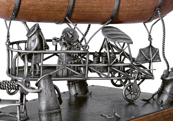 Book cover of Taming the Beast: Silver by Earl Krentzin, featuring a silver sculpture of open roofed car with bird at wheel, and creature balancing on orange egg to rear. Published by Arnoldsche Art Publishers.