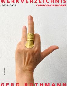 Hand bearing gold ring resembling skin texture, to middle finger, off white cover, WERKVERZEICHNIS 2009-2022 GERD ROTHMANN in red, and black font above and below.