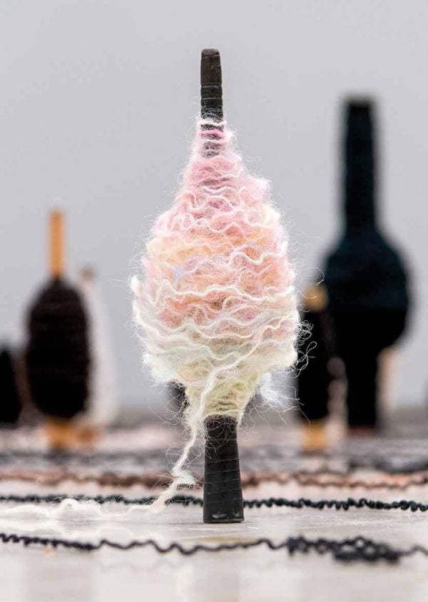 Book cover of Kari Steihaug, with a spinning spool bound with wavy wool in pastel colors. Published by Arnoldsche Art Publishers.