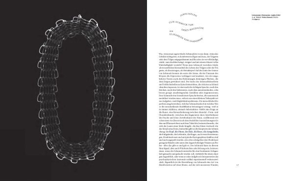 Blue book cover of Gerti Machacek, Jewellery Sculpture, featuring an oxidised copper jewellery piece, shaped like an eye, with eyelashes. Published by Arnoldsche Art Publishers.