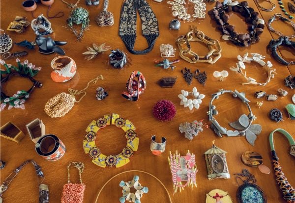 Book cover of Feast: Contemporary Jewelry from the Susan Beech Collection, featuring a figure in red dress wearing a large gold bangle made of cord. Published by Arnoldsche Art Publishers.