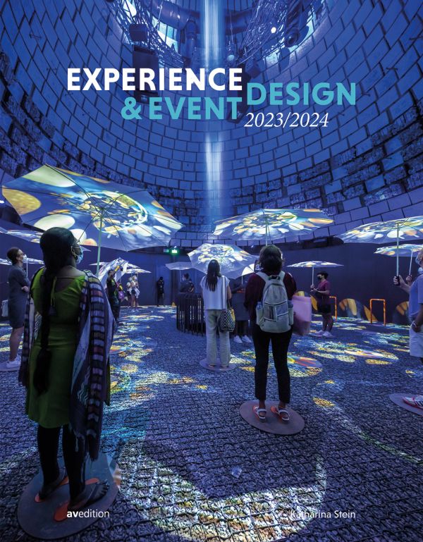 Book cover of Experience & Event Design 2023 / 2024, with exhibition space with people looking up at blue lights and umbrellas. Published by Avedition.