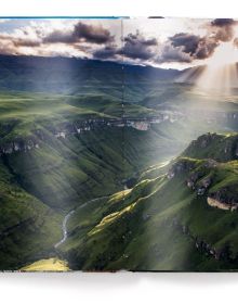 Aerial view of mountainous landscape with river, on cover of 'The World', by teNeues Books.