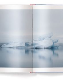 Serene snow covered Scandinavian mountain landscape with pink tinged sky, '6 months in the fridge', in white font above, by teNeues Books.