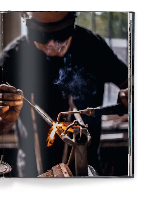 Book cover of Icons of Cycling, featuring two road racing cyclists biking on road with sand hills behind. Published by teNeues Books.