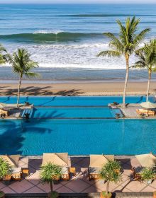 Aerial view of luxury beach resort with palm trees surrounding decked area, 'This Must be Paradise', in white font above.