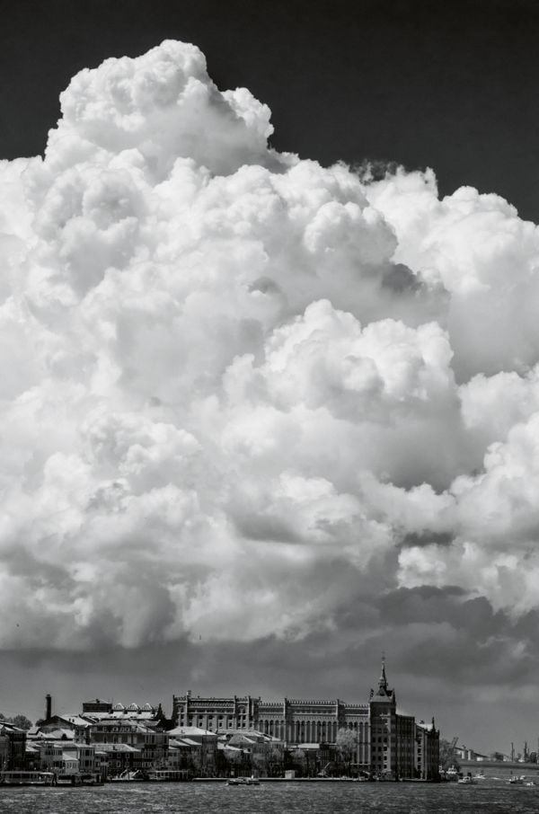 Book cover of Venezia: Through A Venetian's Eye, with a view under arched building of canal in Venice with a man throwing beer barrel in air. Published by teNeues Books.