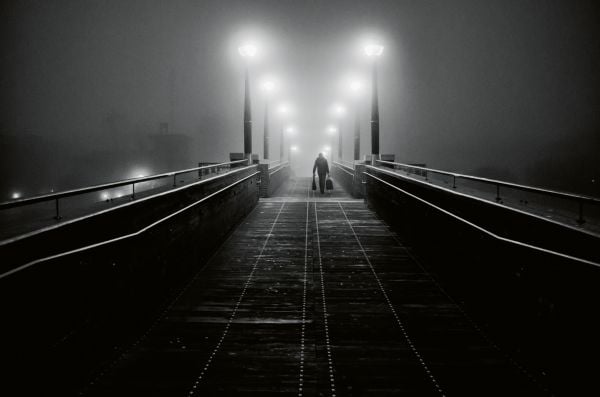Book cover of Venezia: Through A Venetian's Eye, with a view under arched building of canal in Venice with a man throwing beer barrel in air. Published by teNeues Books.