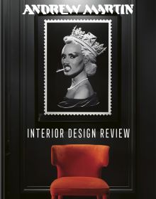 Framed picture of Grace Jones wearing crown, cigarette between teeth, hanging above orange chair, ANDREW MARTIN, in white font above.