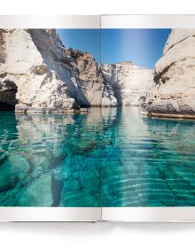 Bright blue and pale green sea of Greek island, small white boat floating to lower right, on white cover, 'CYCLADES', in white font below.