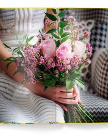 Two light pink roses on green stems, on yellow cover of 'Roses' by teNeues Books.