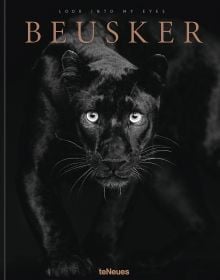 Black panther with silvery-grey eyes staring at the camera, on black cover of 'Beusker, Look into my Eyes', by teNeues Books.