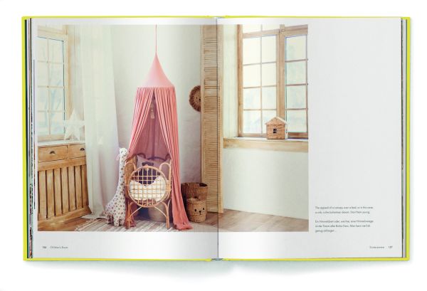 Large rattan chair draped with mustard coloured ceiling fabric, floppy hats on wall, on yellow cover of 'Boho Style, Bohemian Home Inspiration', by teNeues Books.