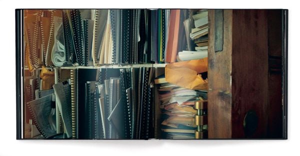 Book cover of dots on paper, Philip Glass by Andreas H. Bitesnich, with the composer in dark jacket, holding circular piece of glass to right eye. Published by teNeues Books.