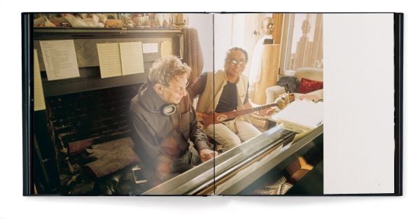 Book cover of dots on paper, Philip Glass by Andreas H. Bitesnich, with the composer in dark jacket, holding circular piece of glass to right eye. Published by teNeues Books.