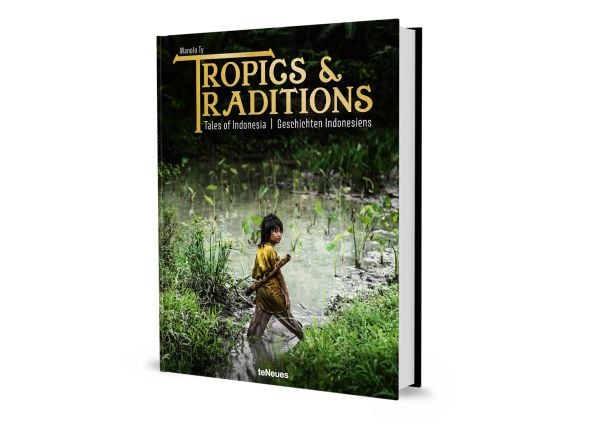 Book cover of Manolo Ty's Tropics & Traditions: Tales of Indonesia, with a young child walking through a river. Published by teNeues Books.