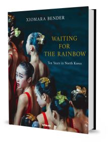 Book cover of Xiomara Bender's Waiting for the Rainbow: Ten Years in North Korea, with a group of dancers lining up in red costumes. Published by teNeues Books.