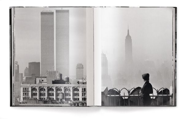 Man wearing white sailor's clothes and hat, with his back to viewer, staring across busy city street, on cover of 'Elliott Erwitt’s New York', by teNeues Books.