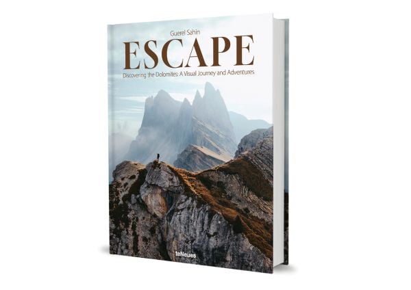 Book cover of Escape: Discovering the Dolomites: A Visual Journey and Adventures; featuring an adventurer standing on top of the Dolomite Mountains. Published by teNeues Books.