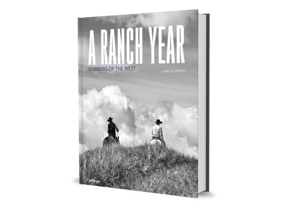 Book cover of A Ranch Year: Cowboys of the West; featuring two figures on horseback riding over a grassy mound, away from the viewer. Published by teNeues Books.