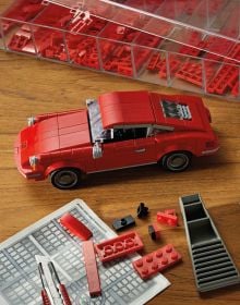 Side profile of three Porsche LEGO models in red, black and white, on cover of 'Porsche 911, Legends Made of LEGO®', by HEEL.