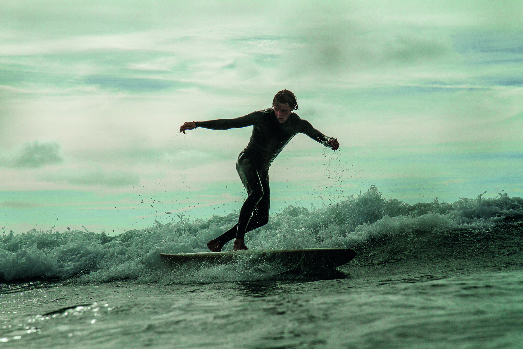 Reflection of male surfer on sand carrying surfboard, on cover of 'The Other Side of Surfing', by Galindo Publishing.