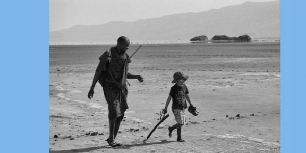 Book cover of Wonder and the World: A Childhood Among the Species, featuring a duotone photograph of a person looking at a large whale swimming near the sea's surface. Published by Verlag Kettler.
