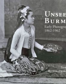 Book cover of Unseen Burma, Early Photography 1862-1962, with a woman in traditional dress, sitting on rug, with hand on cushion. Published by River Books.