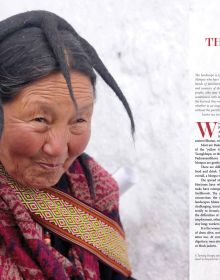 Head and shoulder shot of Monpa tribal woman gazing happily to her left in front of white wall, Monpas in large red font above