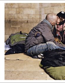 Book cover of Andres Serrano; with a homeless man laying under cardboard. Published by Silvana.