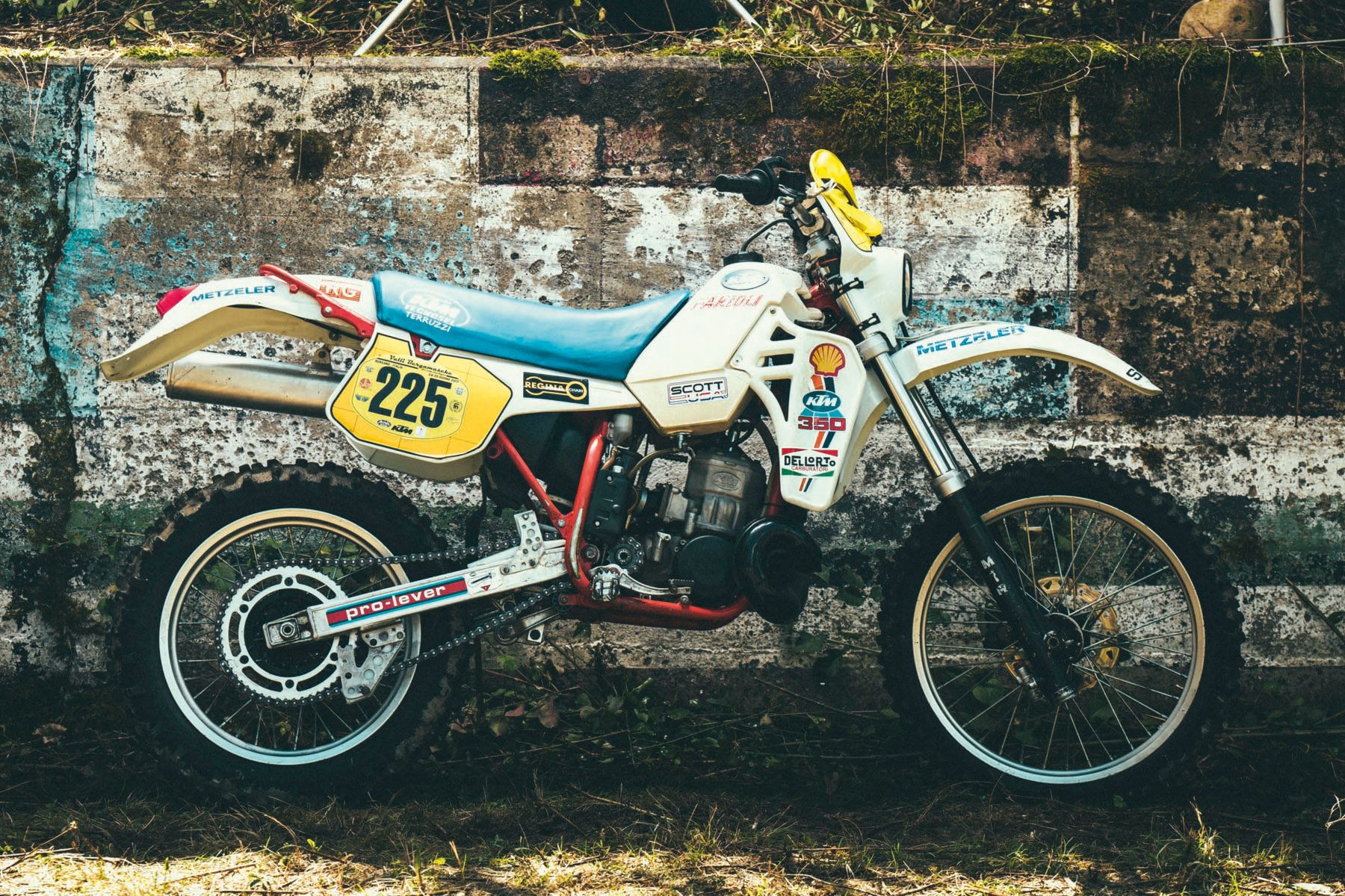 Head of biker with red helmet, peak visor and goggles, dark blue cover, Deus Ex-Machina SWANK RALLY in off white font near centre