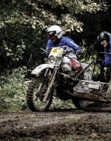 Head of biker with red helmet, peak visor and goggles, dark blue cover, Deus Ex-Machina SWANK RALLY in off white font near centre