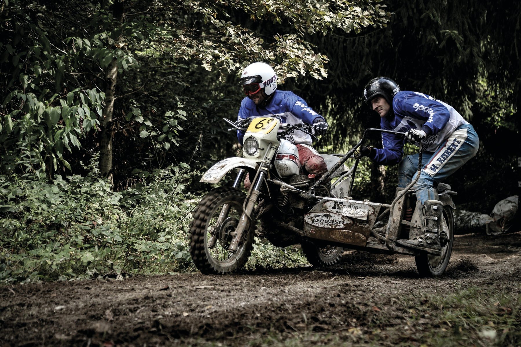 Head of biker with red helmet, peak visor and goggles, dark blue cover, Deus Ex-Machina SWANK RALLY in off white font near centre