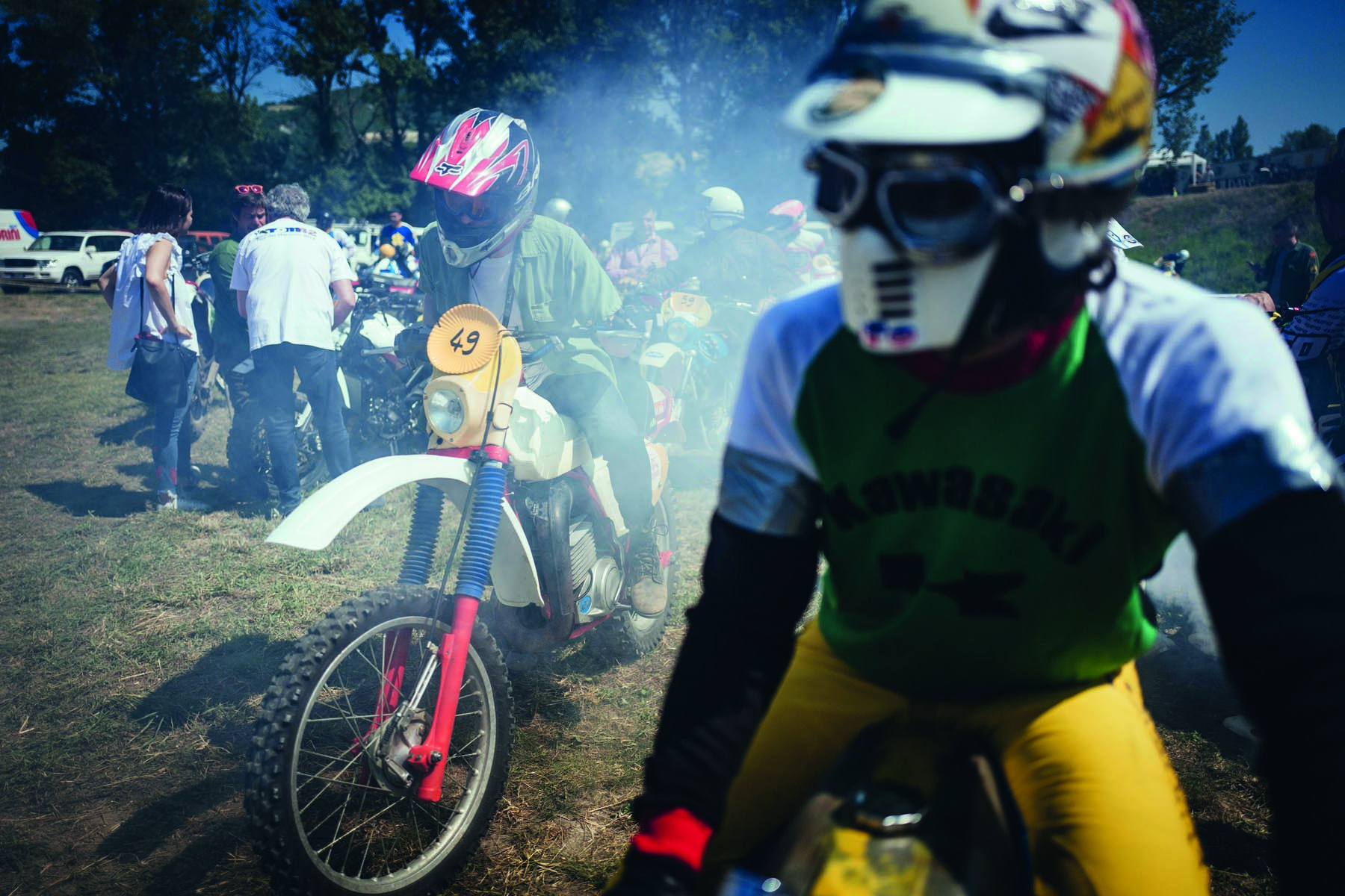 Head of biker with red helmet, peak visor and goggles, dark blue cover, Deus Ex-Machina SWANK RALLY in off white font near centre