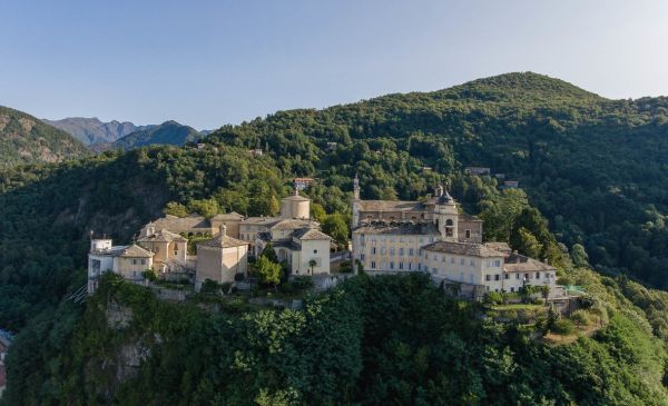 Illuminated front of one of the Chapels of The Sacri Monti, under night sky, I SACRI MONTI in white font to upper left.