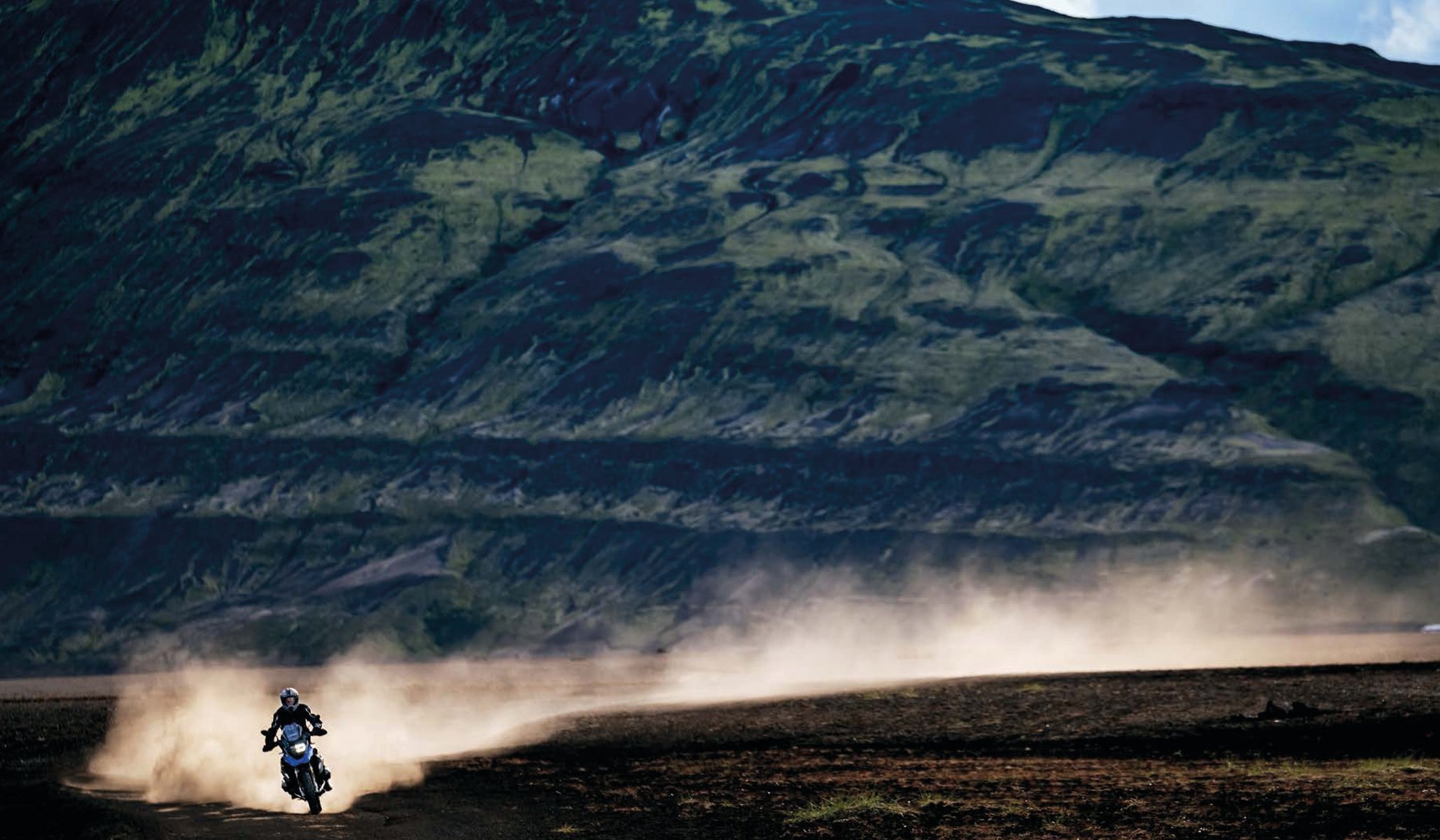 Book cover of The 5th Element: Motorcycle. Adventure. Iceland, with a vast Icelandic mountainous landscape with dirt trail below. Published by Silvana.
