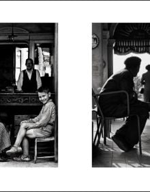 Black and white shot, People of Emilia, Emilia-Romagna 1959, 3 males seated outside café with motorcycle, NINO MIGLIORI in white font to top right.