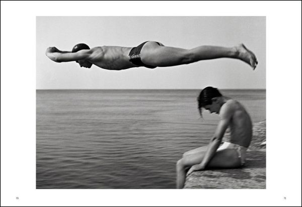 Black and white shot, People of Emilia, Emilia-Romagna 1959, 3 males seated outside café with motorcycle, NINO MIGLIORI in white font to top right.