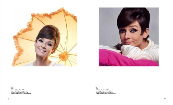 Marilyn Monroe in playful pose, laying beneath a white sheet on bed, Douglas Kirkland in black font to upper left.