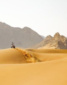 Book cover of Dream Wilder', with a Ducati DesertX off-road motorcycle with rider, speeding across a sandy desert, with sand spray behind. Published by Silvana.