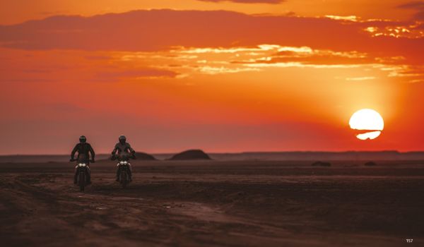 Book cover of Dream Wilder', with a Ducati DesertX off-road motorcycle with rider, speeding across a sandy desert, with sand spray behind. Published by Silvana.