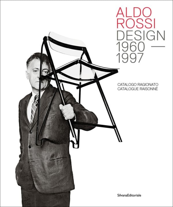 Book cover of Aldo Rossi: Design - 1960-1997. Catalogue Raisonné, with the designer grasping a black framed clear Perspex chair in left hand. Published by Silvana.