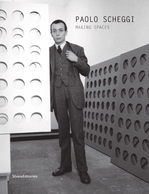 Book cover of Paolo Scheggi, with the Italian artist wearing a suit, standing in a studio surrounded by his elliptical holed canvases. Published by Silvana.
