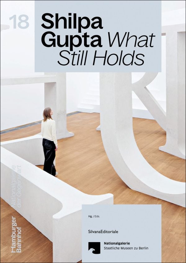 Book cover of Shilpa Gupta: What Still Holds; featuring a person standing among an installation of large white letters. Published by Silvana.