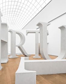 Book cover of Shilpa Gupta: What Still Holds; featuring a person standing among an installation of large white letters. Published by Silvana.