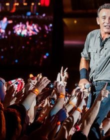 Book cover of Bruce Springsteen, 50 Years of Rock 'n' Roll, with the guitarist on stage at Brendan Byrne Arena, wearing red bandana. Published by White Star.