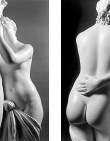 Close up black and white photo of white ancient classical sculpture of male nude model with arm leaning on clothed plinth