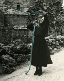 Book cover of Legarsi alla Montagna, Binding to the mountain, featuring a woman in black, stretching out a long blue ribbon through a street. Published by 5 Continents Editions.