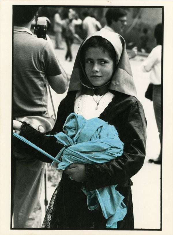 Book cover of Legarsi alla Montagna, Binding to the mountain, featuring a woman in black, stretching out a long blue ribbon through a street. Published by 5 Continents Editions.