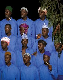 Red book cover of Omar Victor Diop, featuring a portrait photo of black man in black smock and red hat, holding blue exotic bird, titled 'Allegoria 1, 2021'. Published by 5 Continents Editions.